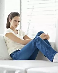 Frau sitzt auf Couch mit HempAge Hanf T-Shirt Breeze Farbe offwhite